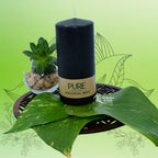 Bougie pilier noire « PURE » en cire naturelle, étiquette kraft, sur feuille verte avec plante succulente (L’Echoppe de Gaïa).