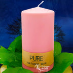 Bougie pilier rose en cire naturelle « PURE », avec étiquette beige, posée sur des feuilles vertes (L’Echoppe de Gaïa).