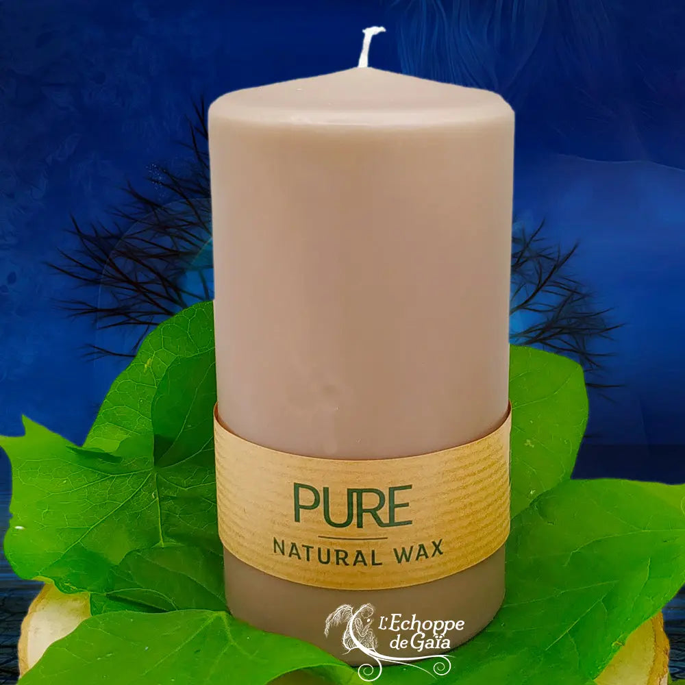 Bougie pilier couleur sable en cire naturelle « PURE », avec étiquette beige, posée sur des feuilles vertes (L’Echoppe de Gaïa).