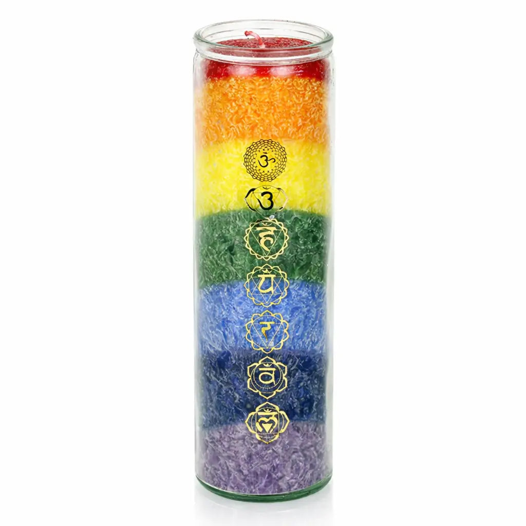Une bougie pilier aux couleurs des 7 chakras dans un haut contenant cylindrique en verre, ornée des symboles sacrés dorés correspondants, présentée sur un fond blanc.