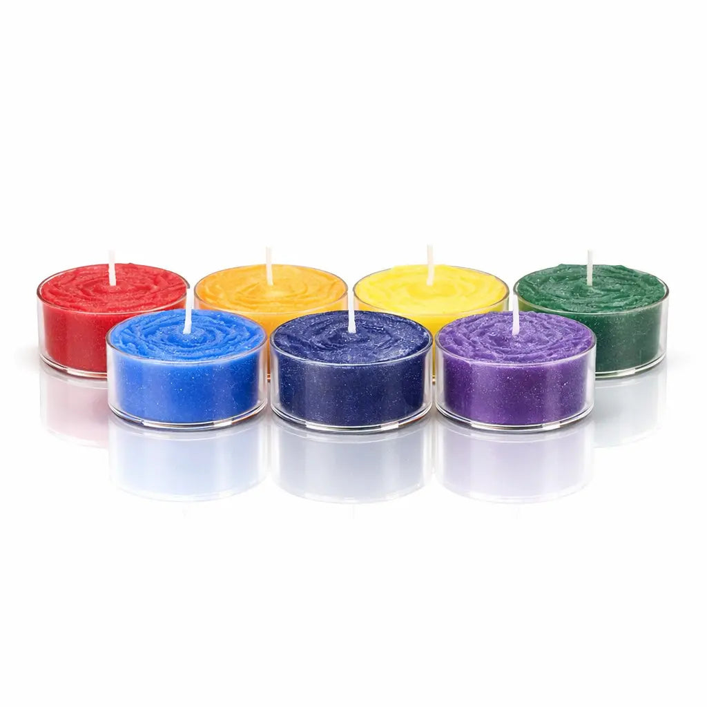 Un lot de sept bougies chauffe-plat aux couleurs des 7 chakras, présentées dans des contenants transparents sur un fond blanc avec un reflet à leur base.