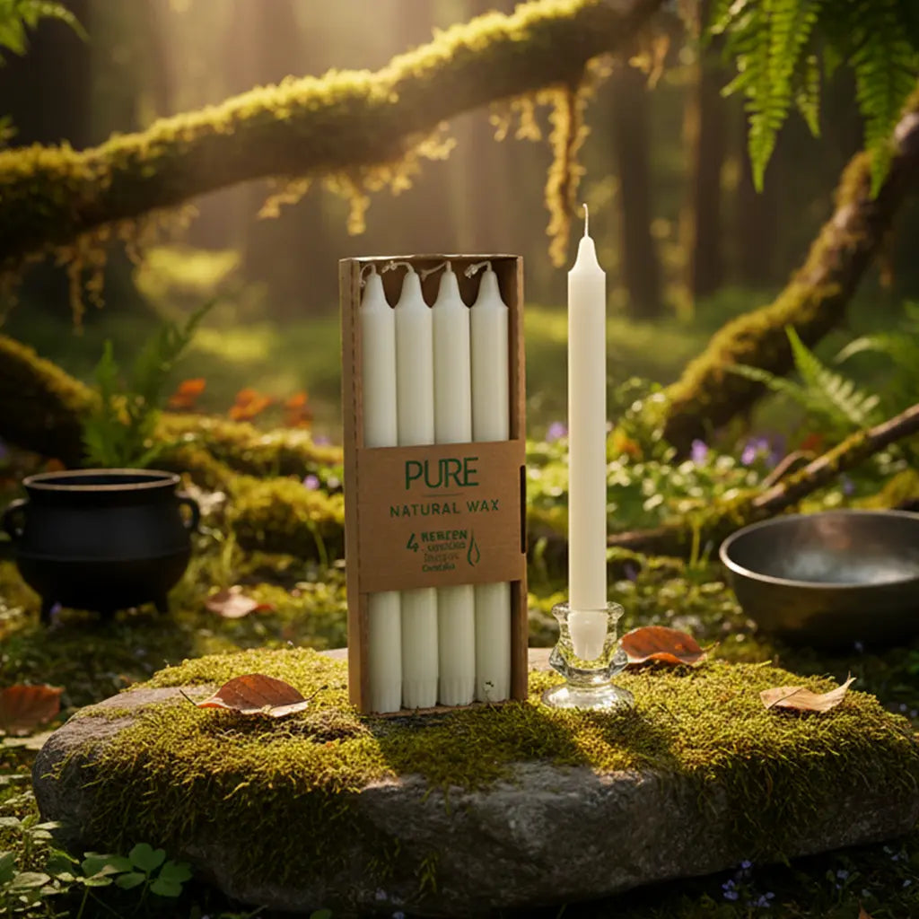 Boîte de 4 bougies longues blanches Pure Candle posée verticalement sur un rocher moussu en forêt, accompagnée d'un petit chaudron et d'un bol chantant pour un rituel de magie blanche.