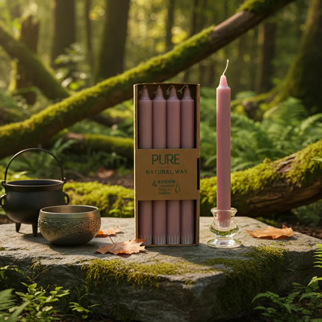 Boîte de 4 bougies longues rose antique Pure Candle posée sur un rocher moussu en forêt, accompagnée d'un petit chaudron et d'un bol chantant pour un rituel d'amour et de douceur.