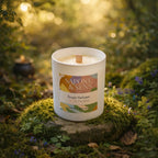 Bougie parfumée artisanale Ambre Précieux avec mèche en bois posée sur un socle de mousse en forêt.
