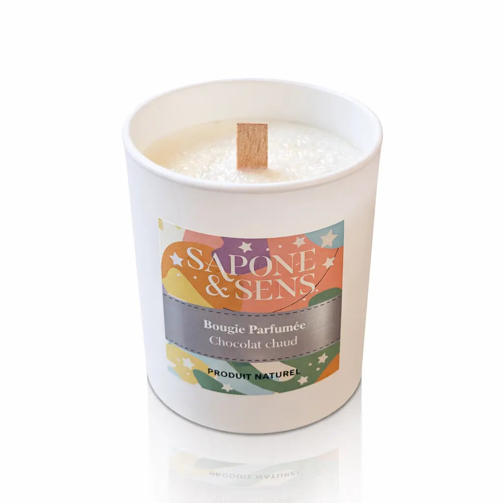 Une bougie parfumée naturelle « Chocolat chaud » de la marque Sapone & Sens, présentée dans un pot en céramique blanche avec une mèche en bois, sur un fond blanc.