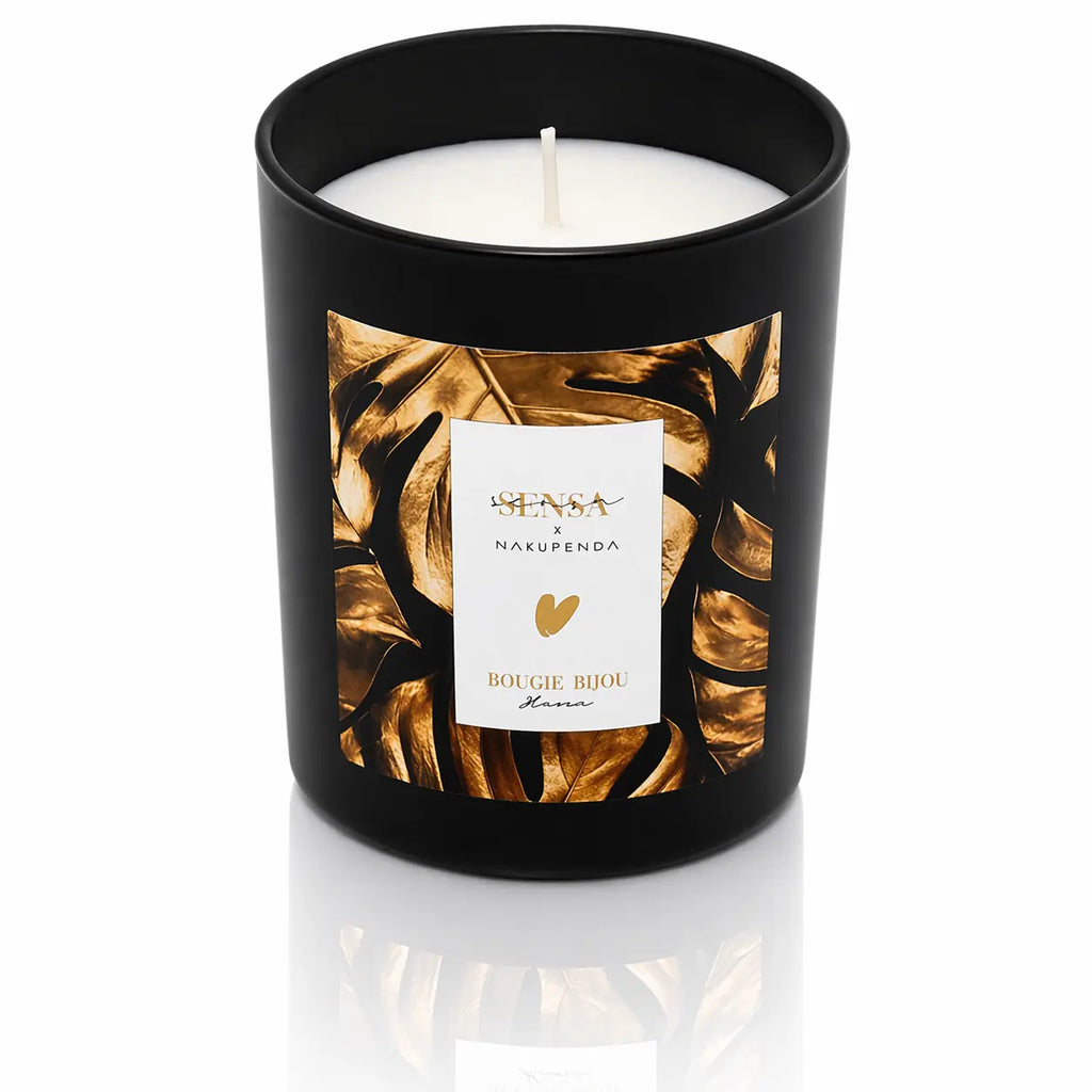 Bougie bijou Sensa x Nakupenda "Hana" dans un pot noir mat avec étiquette feuilles de monstera dorées.