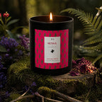 Bougie parfumée Eskalia Escale Mexique à l'étiquette rouge et noire, allumée sur une souche de bois moussue entourée de fleurs violettes et de fougères dans un sous-bois.