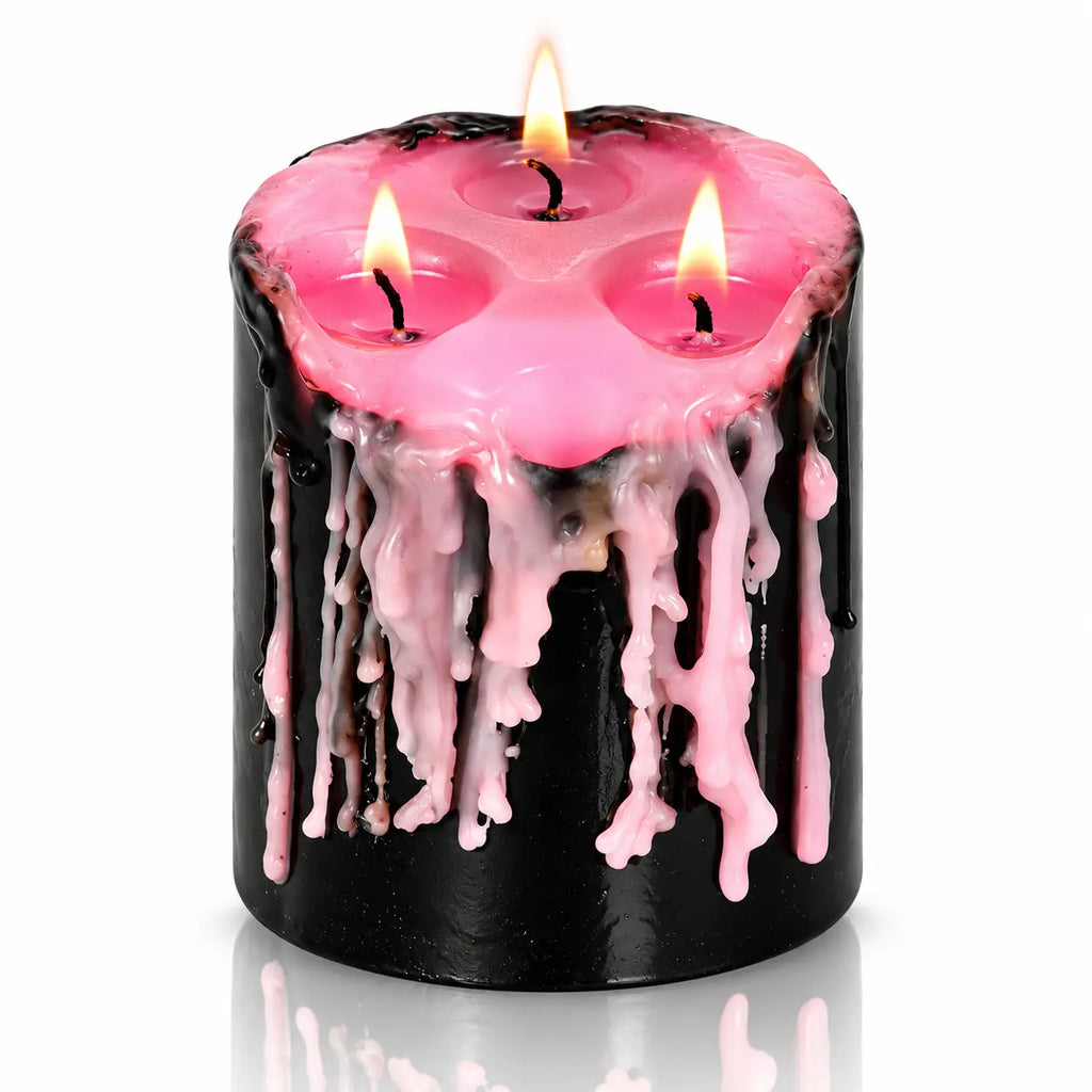Bougie Antique Vampire Draculina 3 Mèches noire allumée laissant couler de la cire rose, sur fond blanc neutre.   