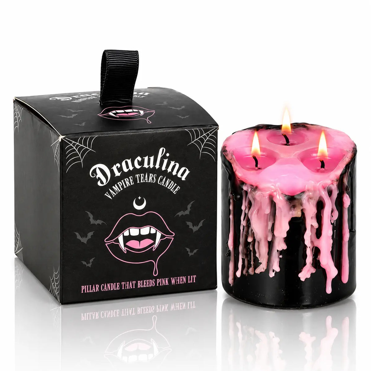 Bougie Antique Vampire Draculina 3 Mèches allumée à la cire rose à côté de sa boîte noire sur fond blanc.   