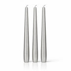 Un lot de trois bougies flambeaux métallisées argentées, de forme effilée et élégante, présentées debout sur un fond blanc avec un léger reflet à leur base.
