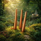 Lot de trois bougies métalisées flambeau cuivre de 25 cm de haut dans un décor forestier mystique.