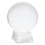 Boule de cristal transparente (sphère en verre) posée sur un socle/pied facetté en verre ou acrylique, présentée sur fond blanc.
