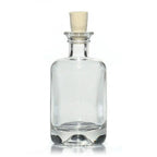Une petite bouteille en verre transparent de type apothicaire avec un bouchon en liège, idéale pour contenir des élixirs ou des potions, présentée sur un fond blanc.