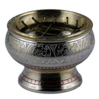 Encensoir sur socle en métal couleur argent, motifs gravés en frise, liserés rouges sur la base, grille supérieure croisée, fond blanc.