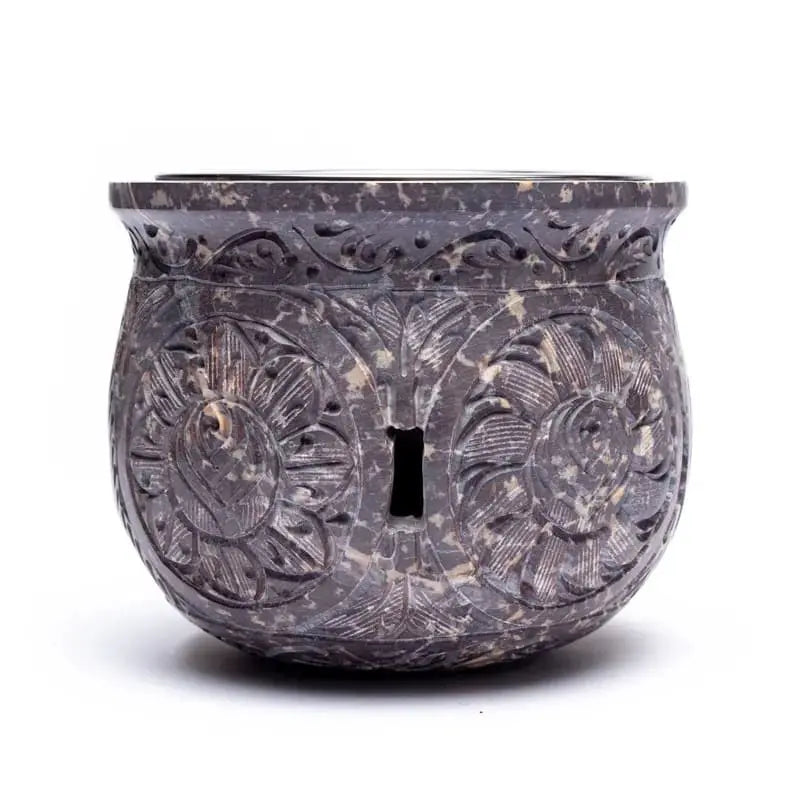 Brûle-encens en pierre stéatite sombre effet marbré, forme ronde décorée de fleurs sculptées, fente ajourée au centre, fond blanc.