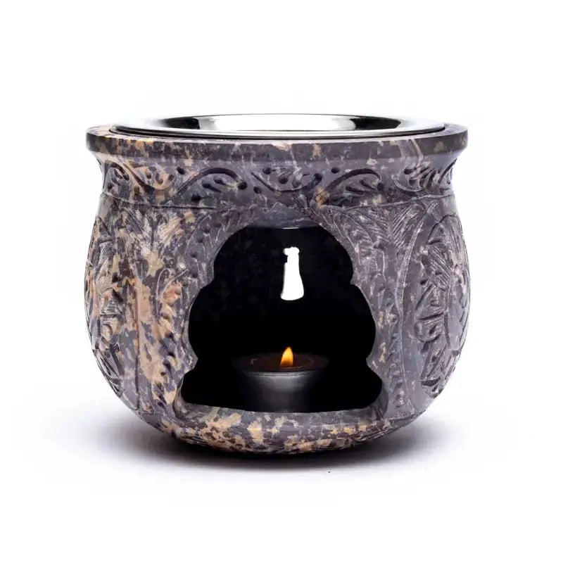 Brûle-encens en pierre stéatite sombre effet marbré, décor floral sculpté, cavité centrale avec chauffe-plat allumé, fond blanc.