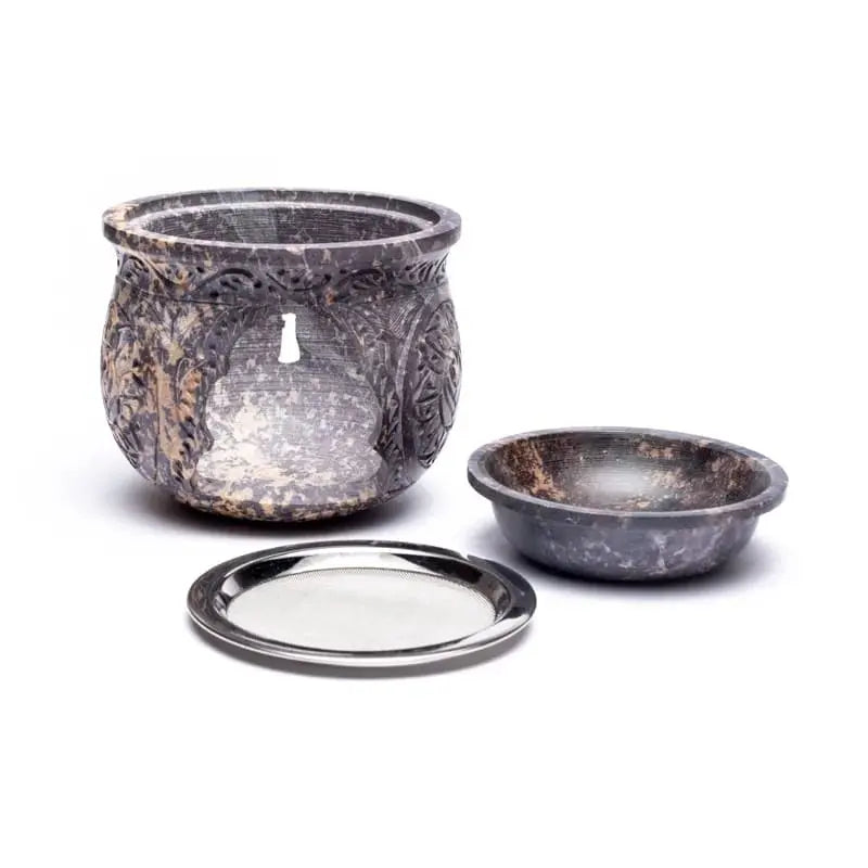 Brûle-encens en pierre stéatite sombre effet marbré, forme ronde ajourée avec décor sculpté, coupelle séparée et tamis métal, fond blanc.