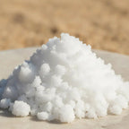 Gros plan sur un tas de cristaux de camphre blancs sur fond flou couleur sable.