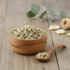 Encens Cathédrale en grains jaunes et gris dans une coupelle en bois avec petite cuillère sur table en bois.