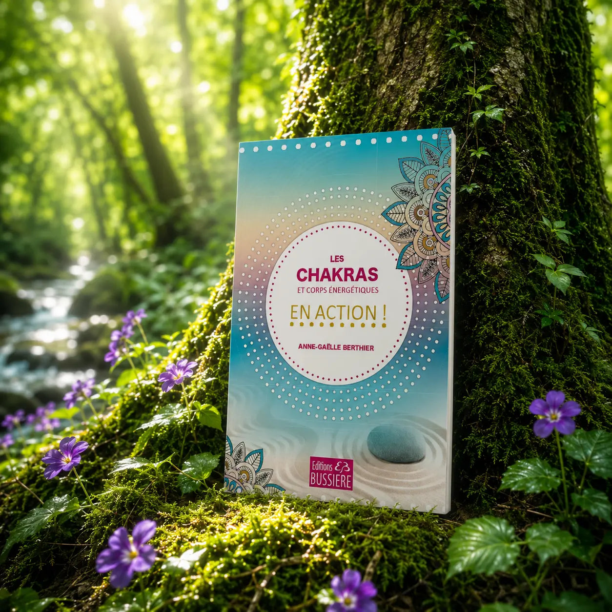 Livre Les Chakras et Corps Energétiques en Action ! sur mousse sacrée au pied d'un arbre, entouré de fleurs violettes sous des rayons de soleil magiques.