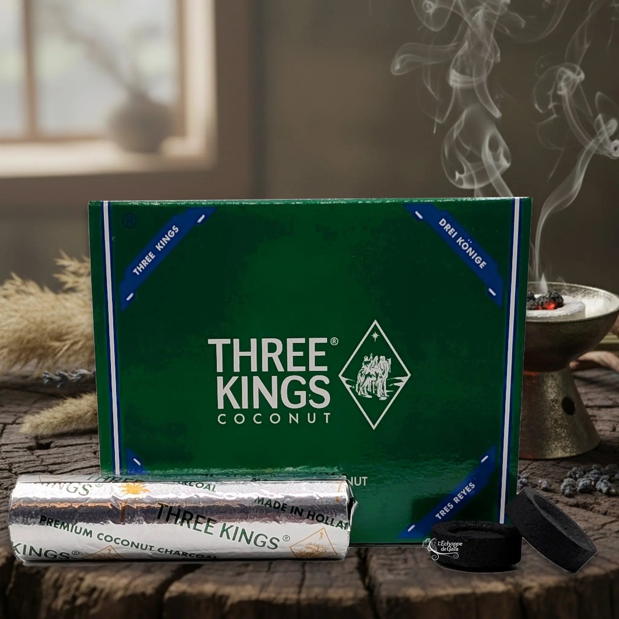 Boîte de Charbons Three Kings Premium Coconut 33 mm naturels, présentée avec son emballage vert, un rouleau argenté et une pastille incandescente dans un brûle-encens.