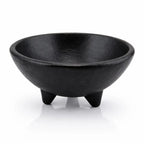 Bol trépied noir mat avec une texture rugueuse et trois pieds coniques sur un fond blanc avec reflet.