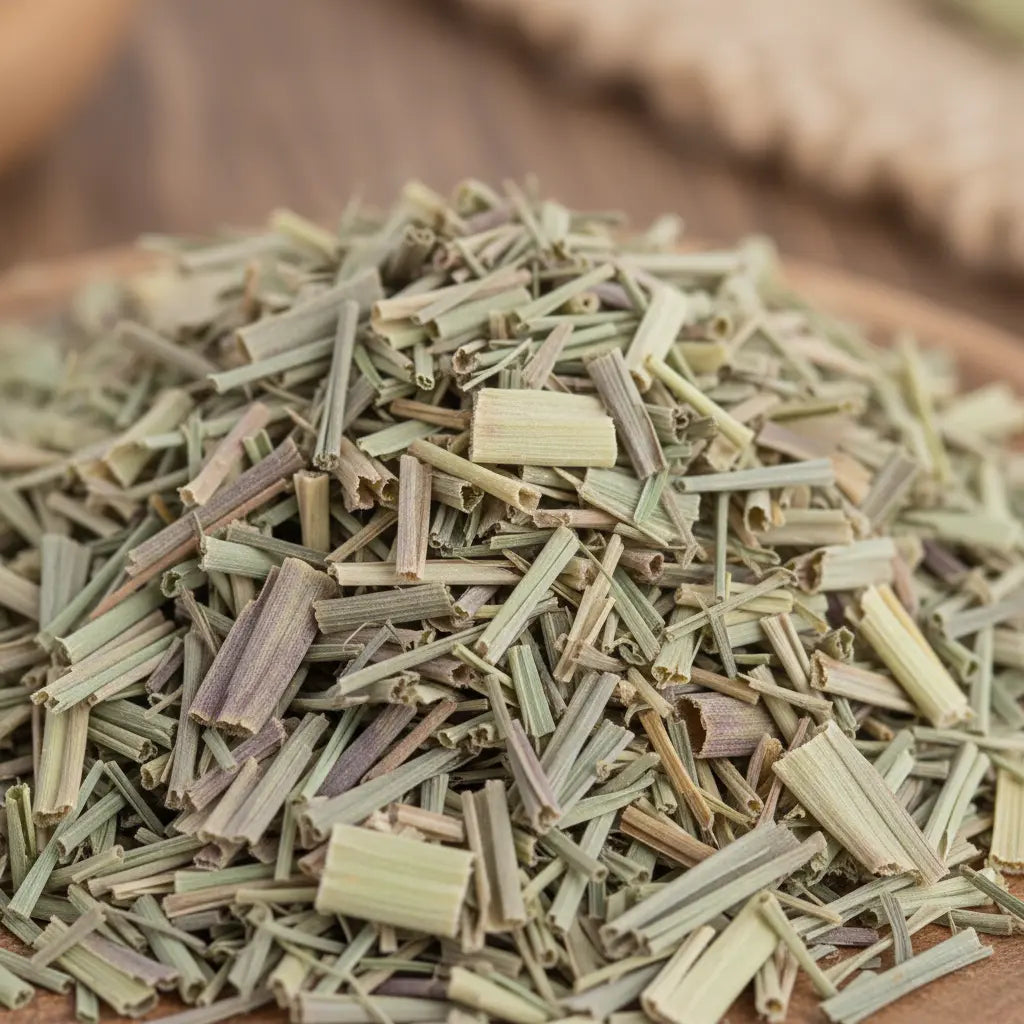 Brins de citronnelle séchée vert pâle coupés en petits morceaux en vrac sur support en bois.
