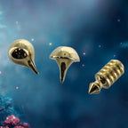 Trois pointes de pendules interchangeables en métal doré, présentant des formes variées pour adapter la précision de l'outil : une forme goutte d'eau lisse, une forme conique évasée et une forme égyptienne (type Thot) avec des disques empilés.