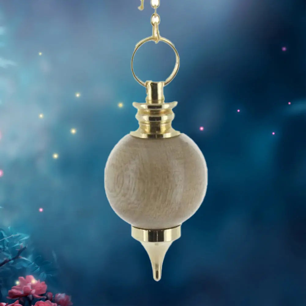 Pendule Séphoroton assemblé avec une sphère en bois clair nervuré, monté sur une armature métallique dorée avec une pointe effilée et un anneau de suspension.