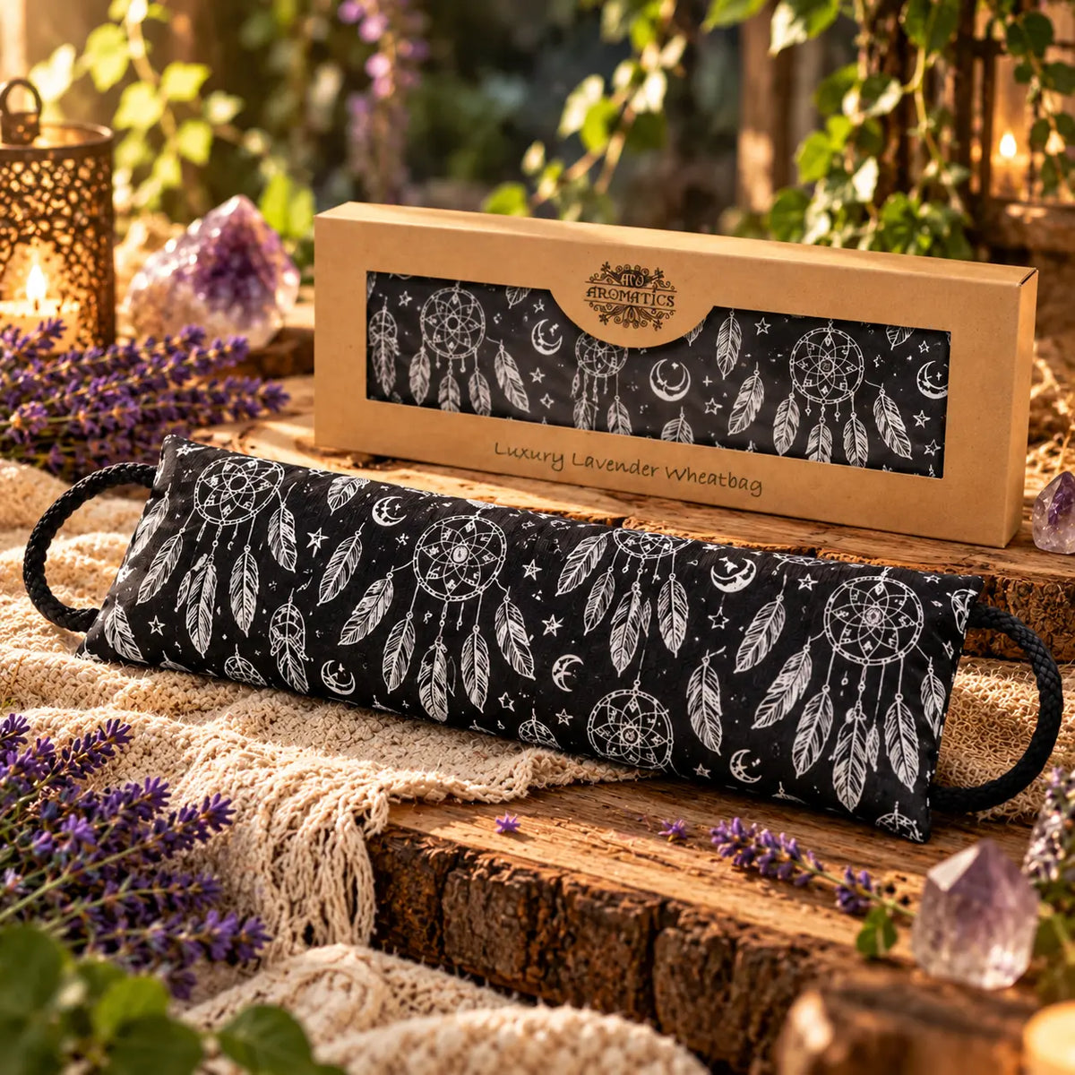Coussin Détente Chauffant - Dream Catcher noir à motifs attrape-rêves posé devant son coffret kraft sur une table en bois.   