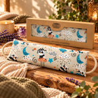 Coussin Détente Chauffant - Panda aux motifs de lune posé devant son coffret kraft sur une table en bois.   