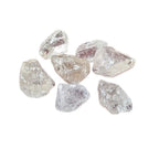 Sept fragments de cristal de roche brut translucides et facettés, aux éclats vitreux naturels, regroupés sur un fond blanc uni.