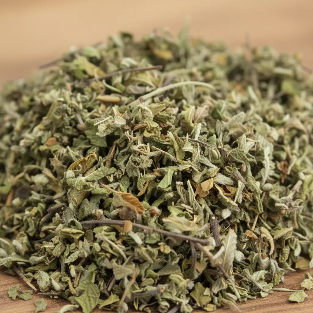 Feuilles de damiana séchées vert pâle en vrac sur surface en bois.