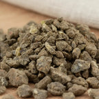 Gros plan sur un monticule de morceaux de résine d'Encens Djaoui Noir, montrant des grains irréguliers de couleur brun-gris foncé et terreux, avec une texture granuleuse.