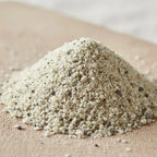 Gros plan sur un monticule d'Encens Église en poudre, montrant de petits grains blanc cassé et gris clair mélangés à des particules noires, sur une surface en bois.