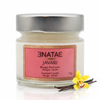 Une bougie parfumée naturelle « Javari » (Mangue - Vanille) de la marque Enatae, présentée dans un petit pot en verre avec couvercle métallique, accompagnée d'une fleur de vanille et de gousses sur un fond blanc.