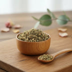 Mélange de plantes séchées et résines d'encens amérindien présenté dans un bol en bois naturel sur une table avec une cuillère en bois et des feuilles d'eucalyptus.