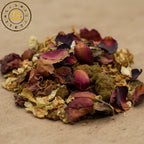 Gros plan sur un mélange d’encens astrologique Balance, composé de pétales de rose séchés et de grains de résine sur fond beige.