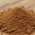 Tas de poudre d’encens ambre patchouli brun, texture fine et légèrement granuleuse, sur surface en bois.