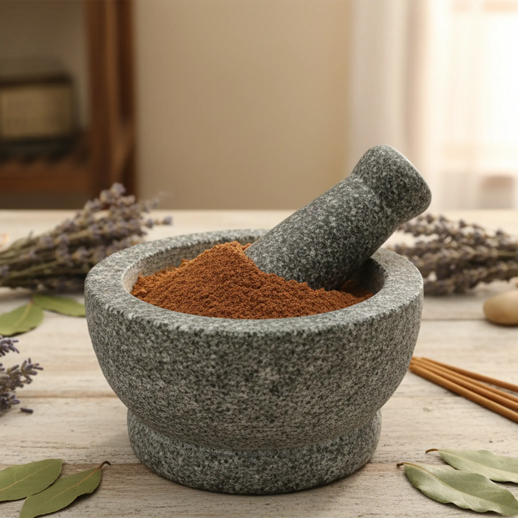 Mortier en pierre rempli de poudre d’encens ambre patchouli brune avec pilon sur table en bois décorée de lavande.