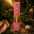 Étui d'Encens Religieux Notre Dame de Fatima de couleur rose marbré, illustré de la Vierge couronnée les mains jointes, disposé près de gousses de vanille et de copeaux de bois.