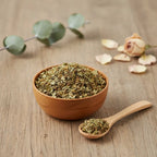 Mélange de résines et de plantes broyées pour le succès dans un bol en bois brun, avec une cuillère, des pétales de fleurs et une branche d'eucalyptus.