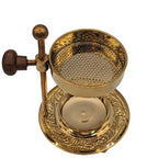 Encensoir réglable en métal doré, coupelle perforée au-dessus d’un réceptacle, molette en bois sur tige, base gravée, sur fond blanc.