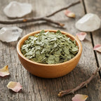 Coupelle en bois remplie de feuilles d’eucalyptus séchées vert pâle sur table en bois avec cristaux et pétales.