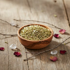 Coupelle en bois remplie de graines de fenouil vert clair sur table en bois avec cristaux et pétales.