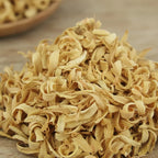 Fleurs d’oranger séchées beige clair en copeaux bouclés en vrac sur surface en bois.