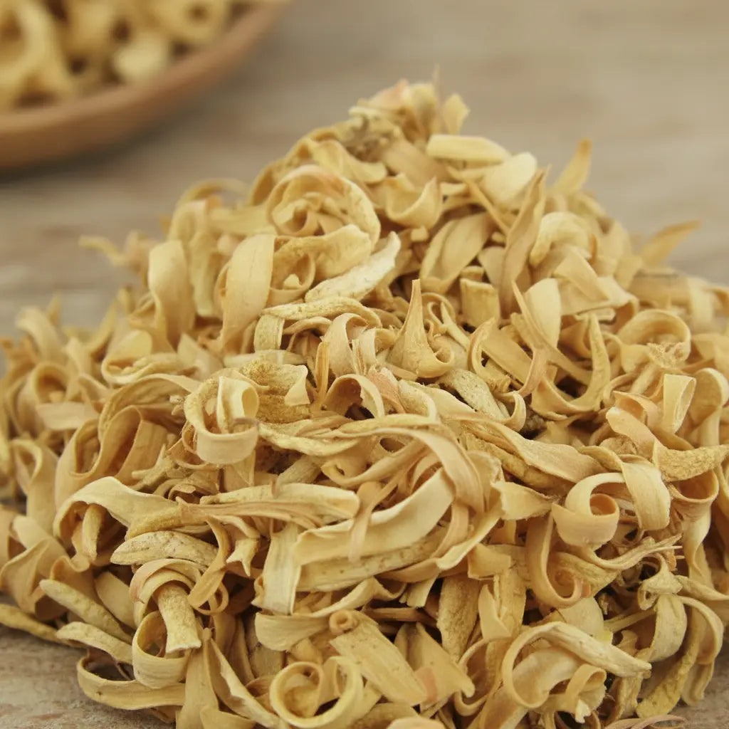Fleurs d’oranger séchées beige clair en copeaux bouclés en vrac sur surface en bois.