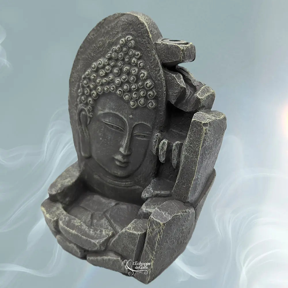 Porte-encens backflow gris foncé aspect pierre, visage de Bouddha et rochers, fond bleu fumé, texte « L’Echoppe de Gaïa ».