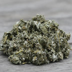 Feuilles de framboisier séchées vert gris en vrac sur surface en bois.