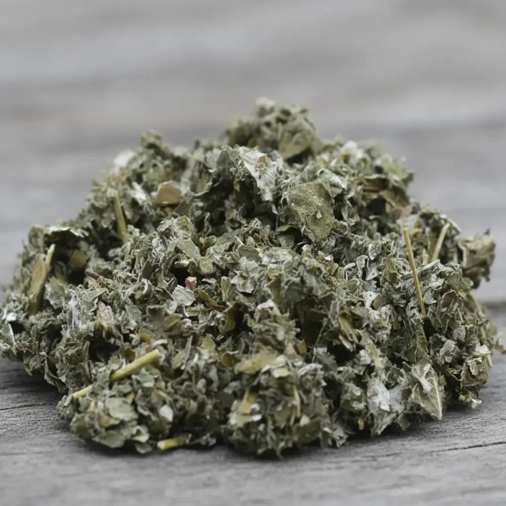 Feuilles de framboisier séchées vert gris en vrac sur surface en bois.